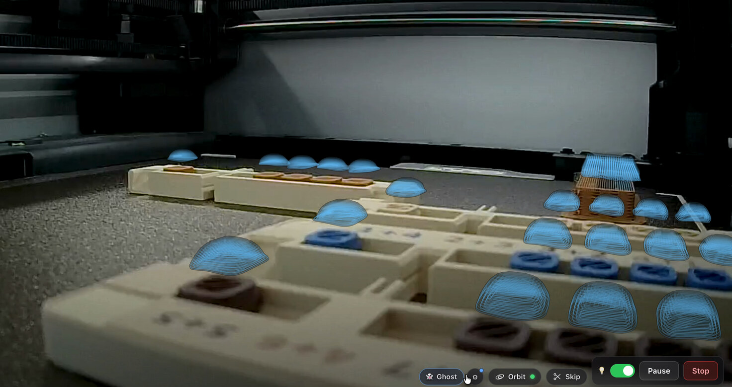 The same camera frame with Ghost switched on: translucent blue domes stand in every bead pocket that has not been printed yet, sitting flush against the printed rails.